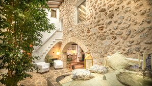 Habitación de paredes de piedra con una escalera, muebles blancos y vista a otra habitación.