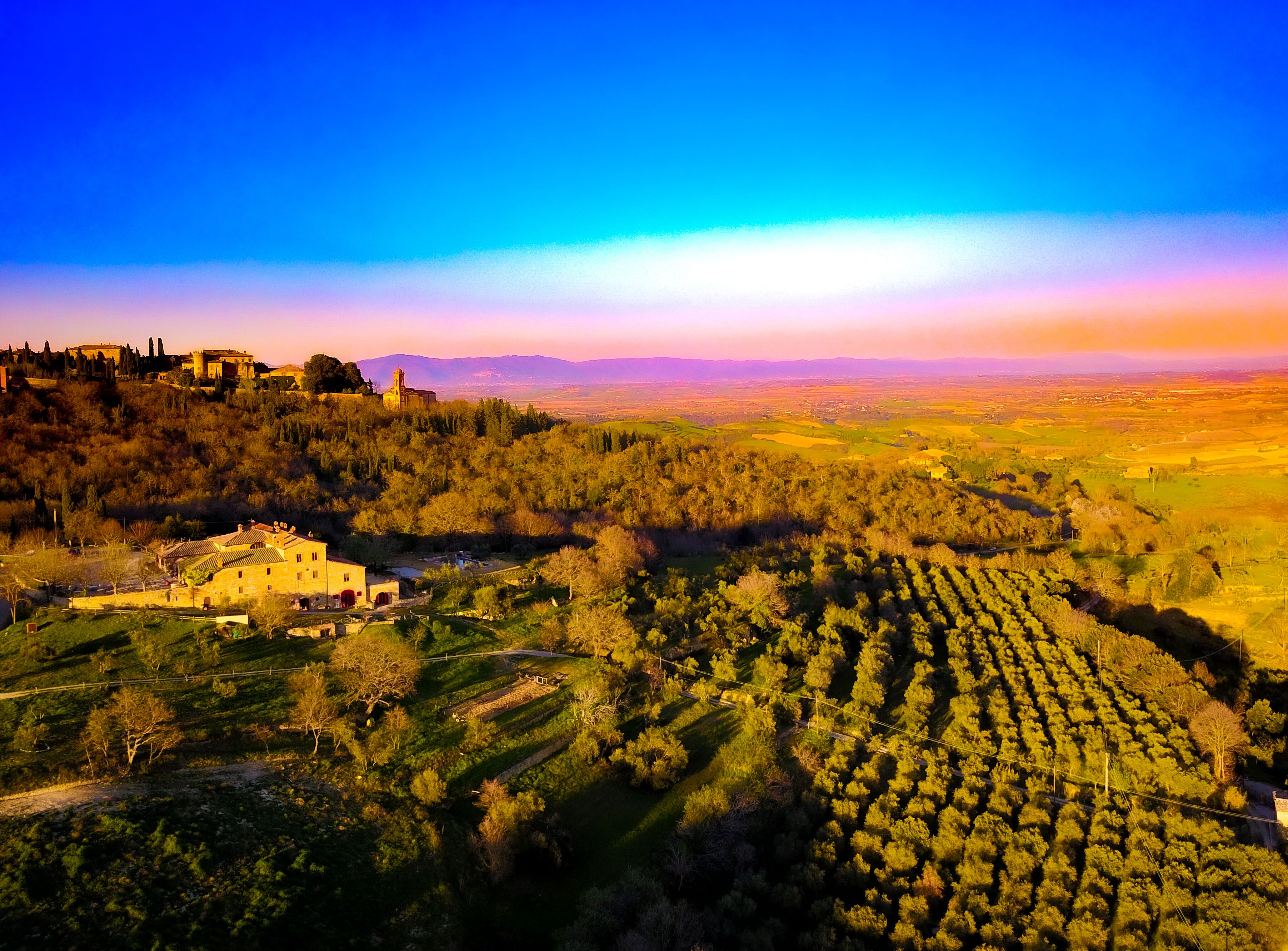 Un paysage rural avec un bâtiment historique, des vignobles en terrasses et des collines ondoyantes.