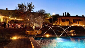 An outdoor pool area with a fountain, string lights, and stone walls. - LaChiusa Tuscany (Torrita di Siena)