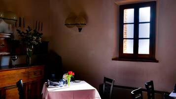 Una sala da pranzo con un tavolo apparecchiato per due, una finestra con vista e illuminazione a parete.