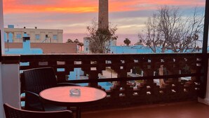 Una terraza con vista a una torre y al atardecer.
