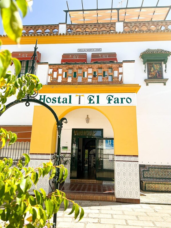 Traditional architecture welcomes you to Hostal El Faro, marked by a grand archway and decorative metal gate.