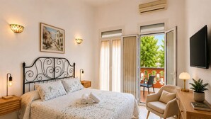 Una habitación de hotel con cama, una silla, un escritorio, televisor y balcón con vistas.