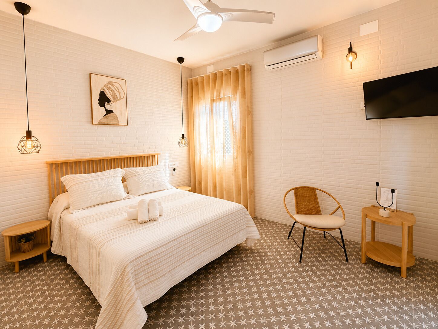 Une chambre d’hôtel avec un lit, une chaise, une télévision et un ventilateur de plafond.
