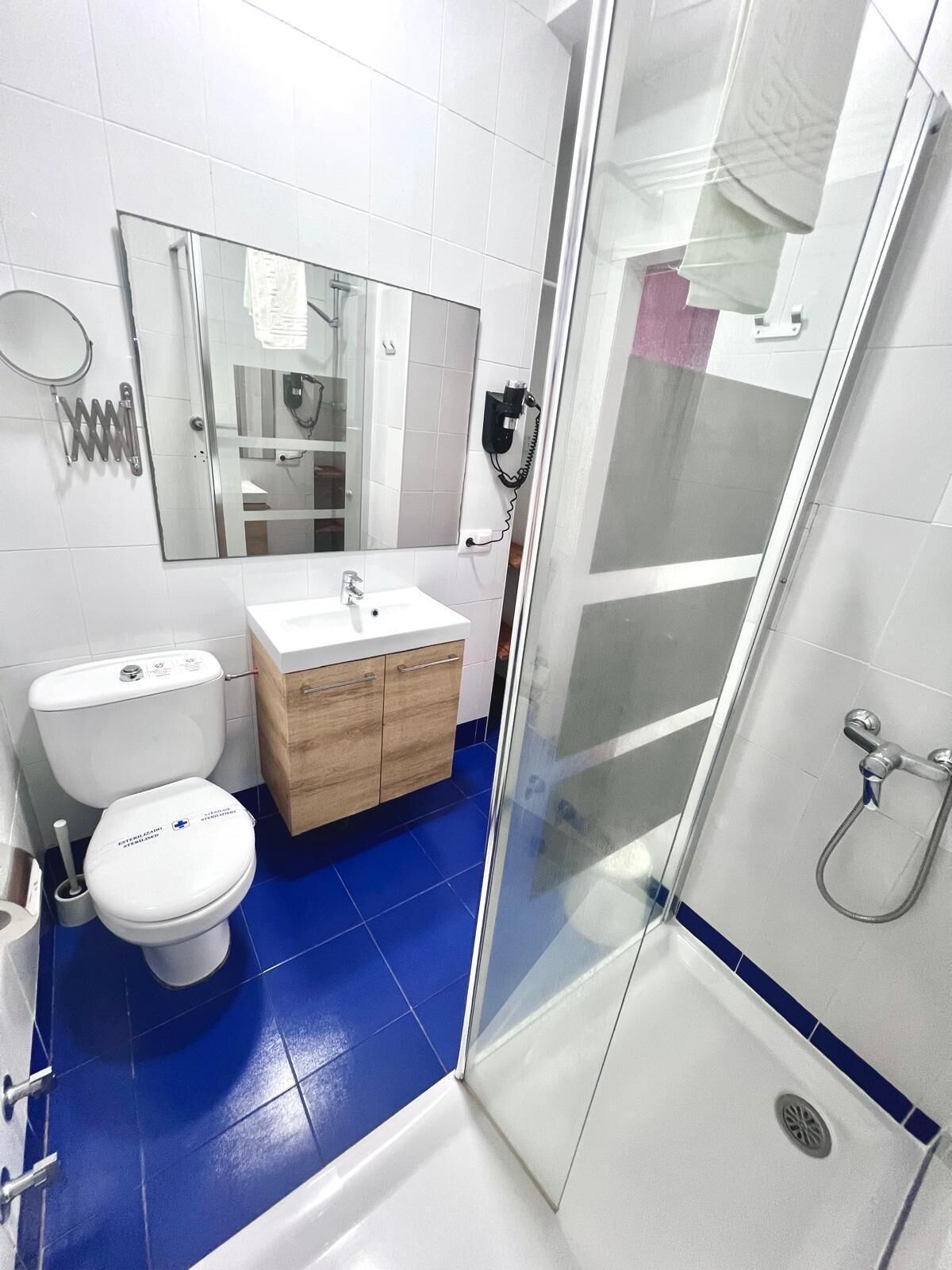 A modern bathroom with a glass shower enclosure, a white toilet, and a wooden vanity.