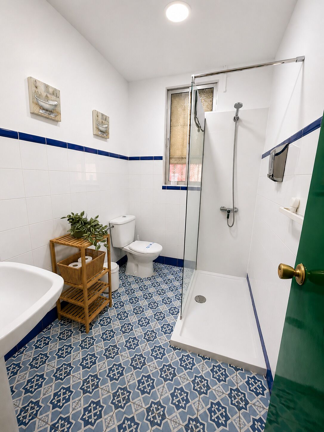Un baño con ducha, inodoro, lavabo y suelo estampado.