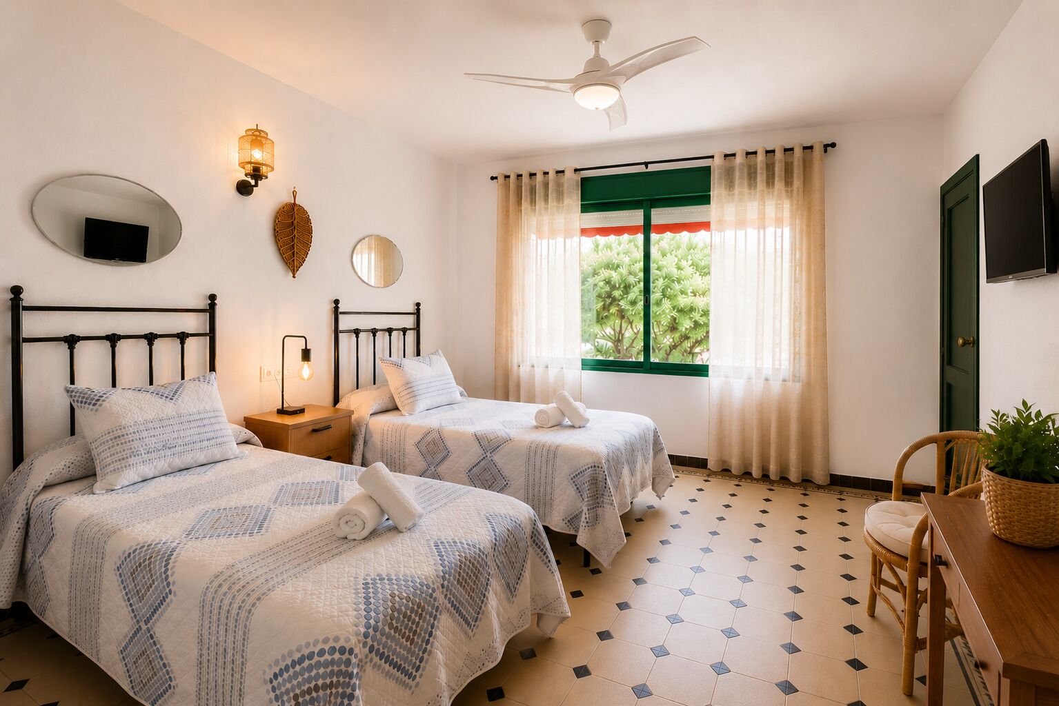 A hotel room with two beds, a ceiling fan, a television, a window with curtains, and a dining area with a chair and table.