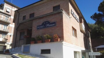 Hotel i Platani, con un letrero, plantas en macetas y un cartel de recepción.
