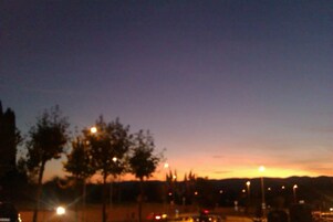 Tramonto su un parco con alberi e lampioni.