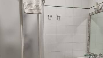 Un baño con ducha a ras de suelo, lavamanos y un taburete pequeño.