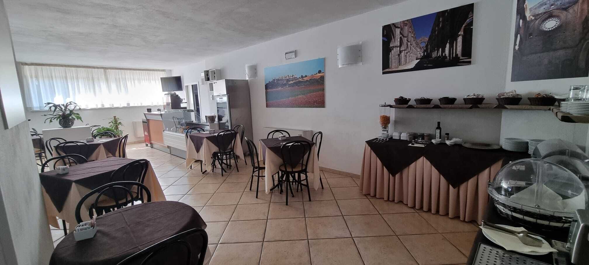 A dining area with multiple tables and chairs, a counter with a display case, and wall-mounted artwork.
