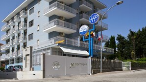 Een meerhoog hotel met balkons, een opvallend 'Hotel President' bord en een heldere blauwe lucht.