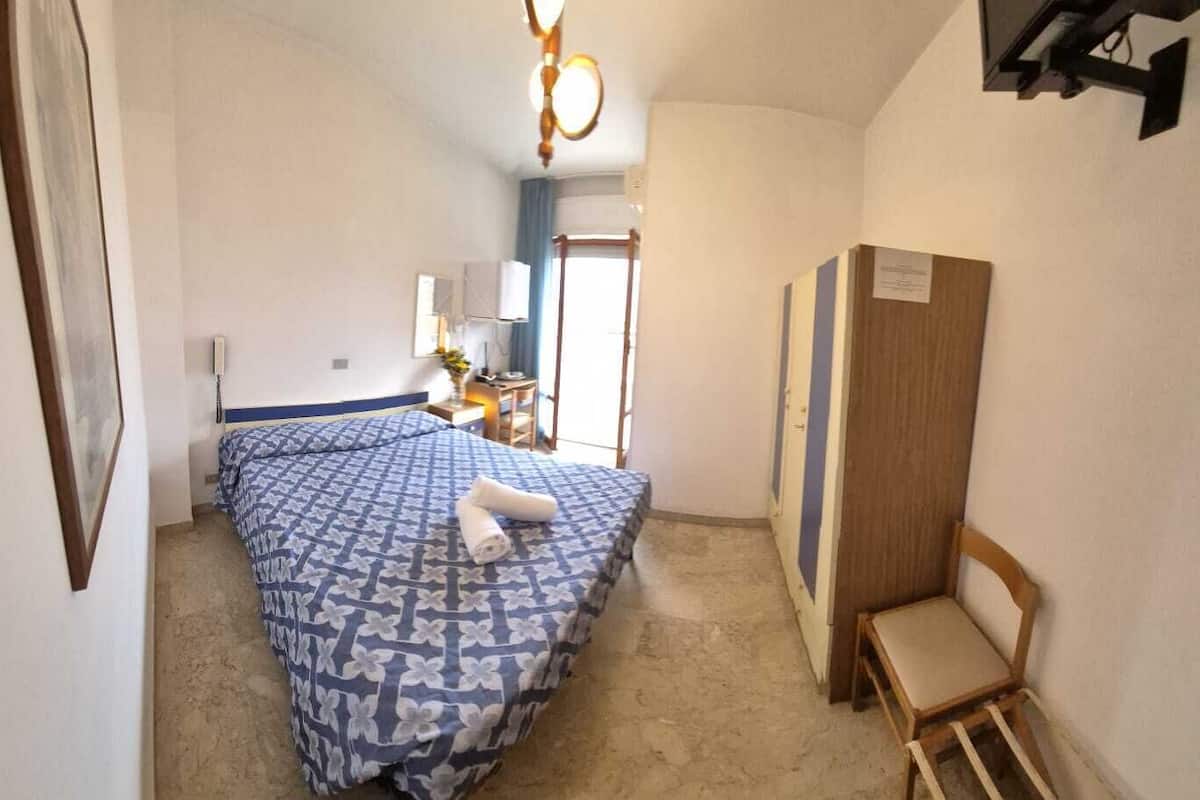 Un dormitorio con cama, escritorio, silla y armario.