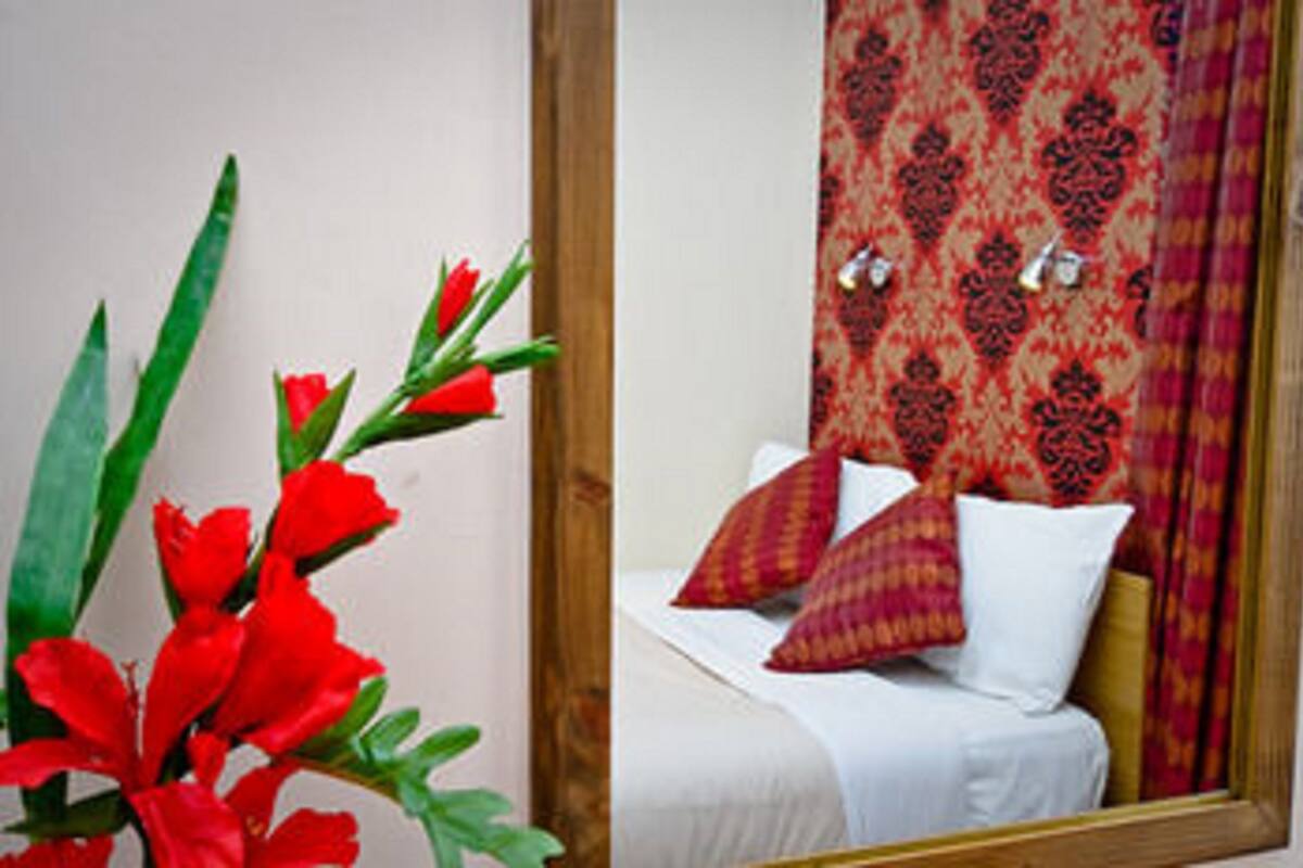 A room with a bed, red patterned curtains, and a mirror.