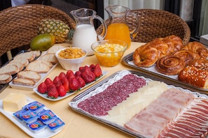 A breakfast buffet with various food items including bread, pastries, fruits, and dairy products. - Miguel de Cervantes (Alcala de Henares)