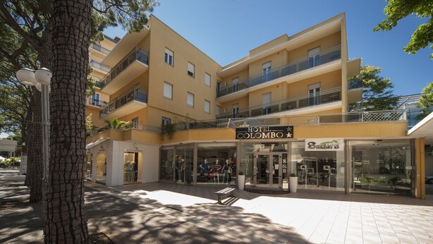 Un hotel con fachada moderna, varios balcones y una entrada despejada.