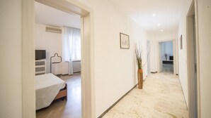 Un pasillo de hotel con una cama, un televisor y una planta.