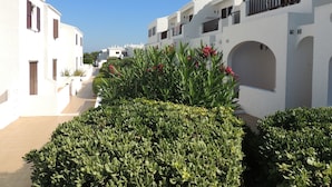 A narrow street lined with white buildings, some with balconies and arched doorways. - Apartamentos Sa Cala (Ciutadella de Menorca)