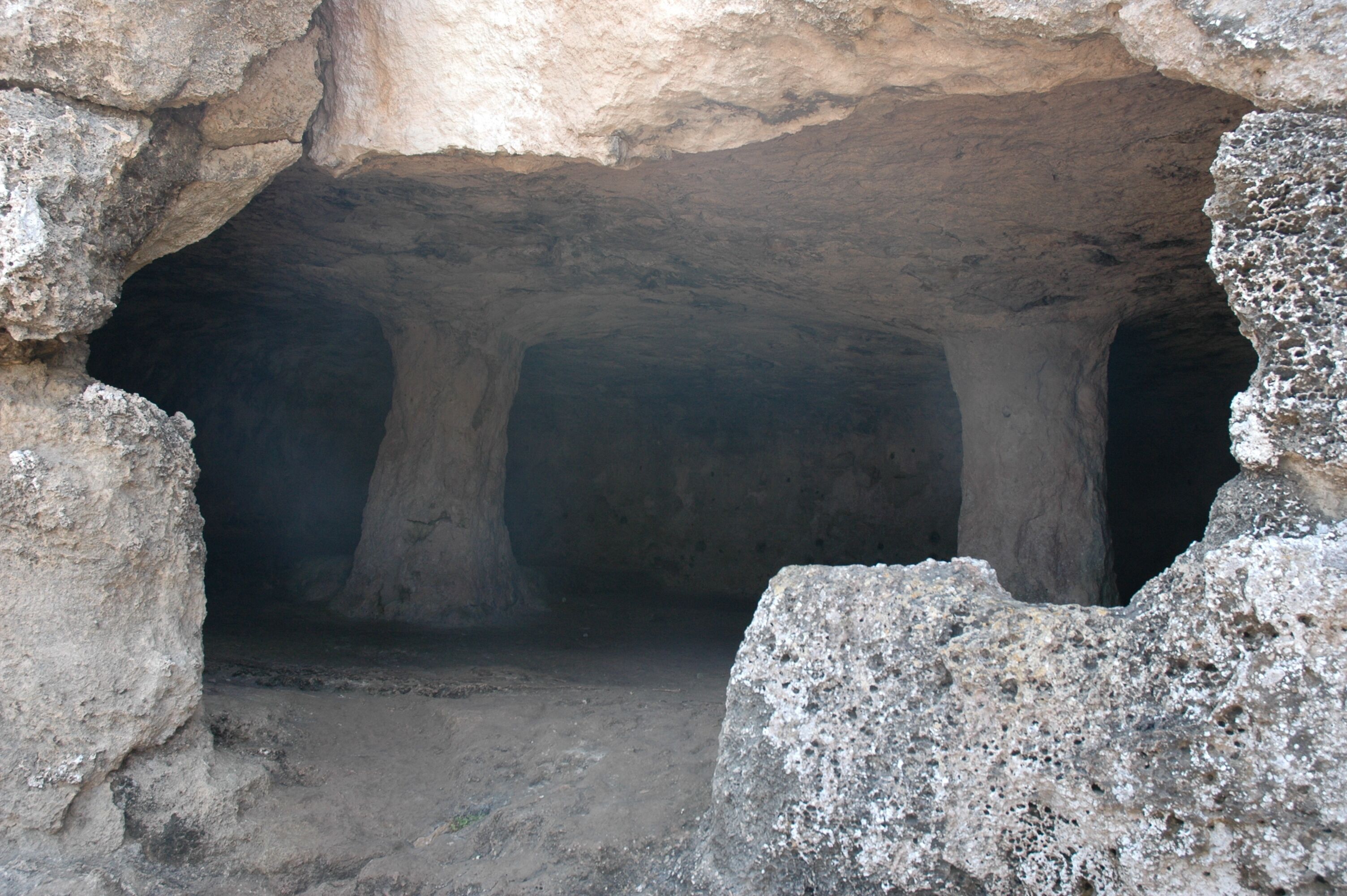 A cave entrance with rough, uneven rock walls and a narrow passageway.