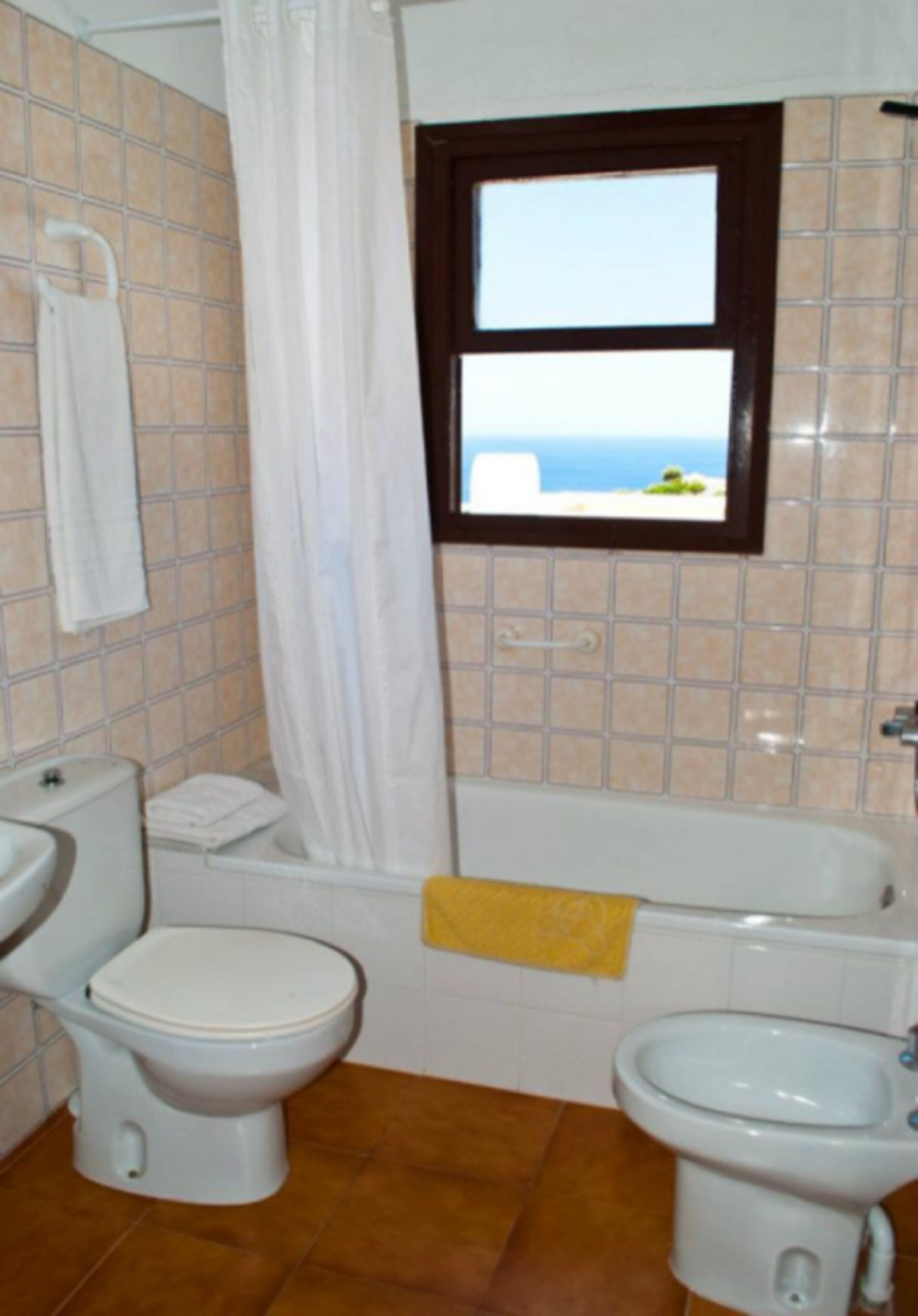 Een badkamer met toilet, hygiëneschuimer en bad.