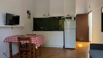 Een kleine keuken met een eettafel, een televisie en een koelkast.