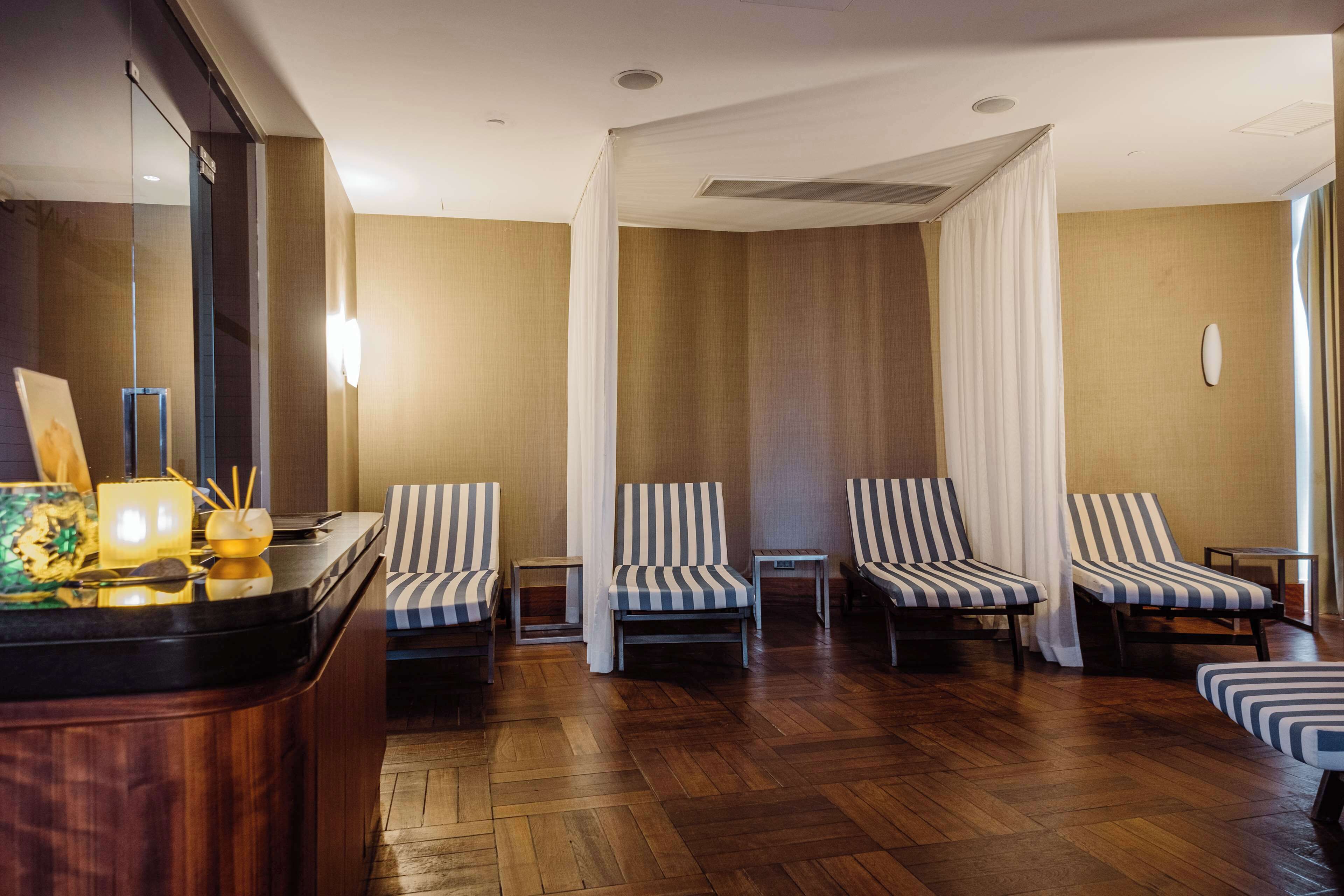 Una habitación con piso de madera, sillones a rayas, una mesita y una cortina.