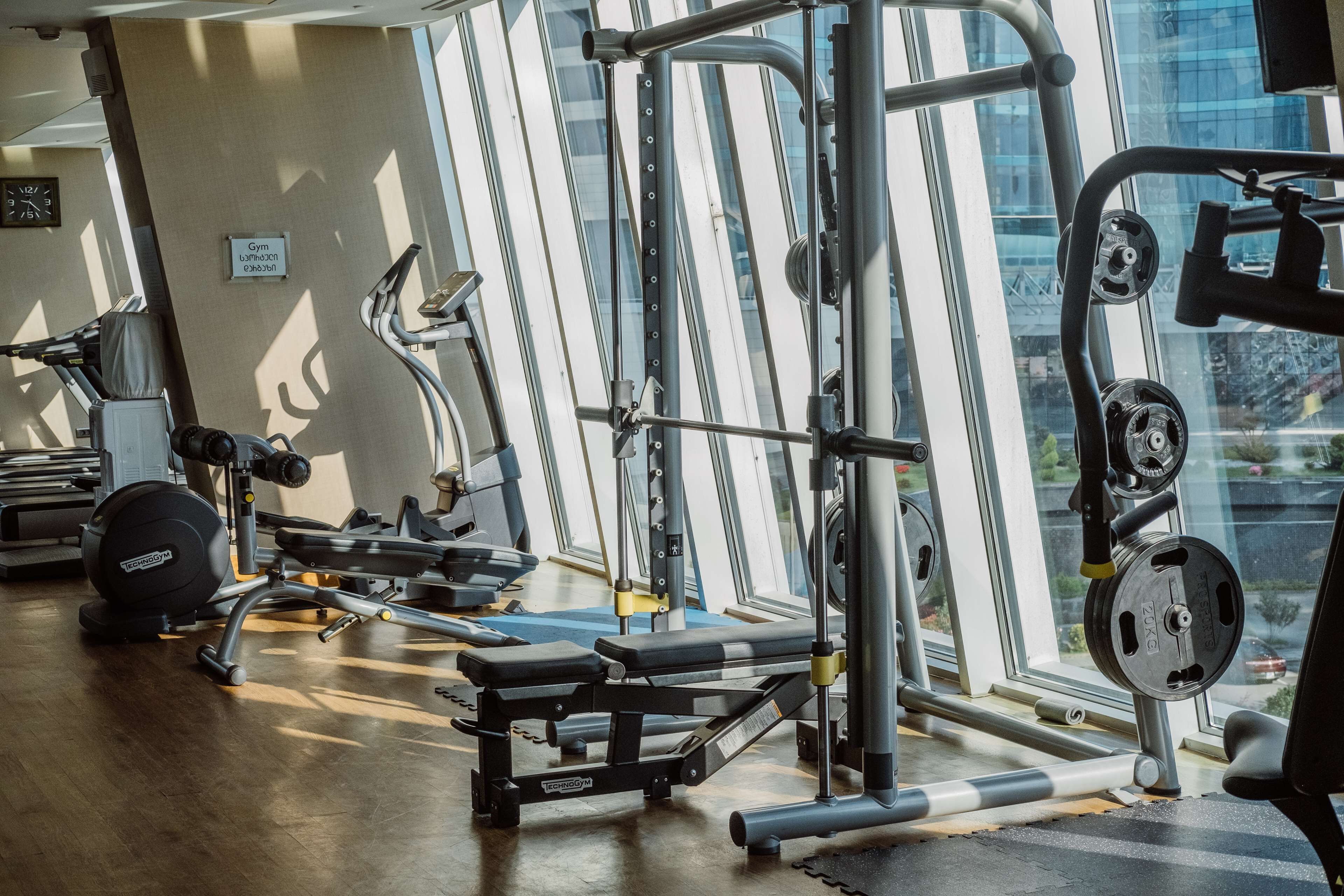 A gym with exercise equipment, large windows, and a sign indicating it is a gym.
