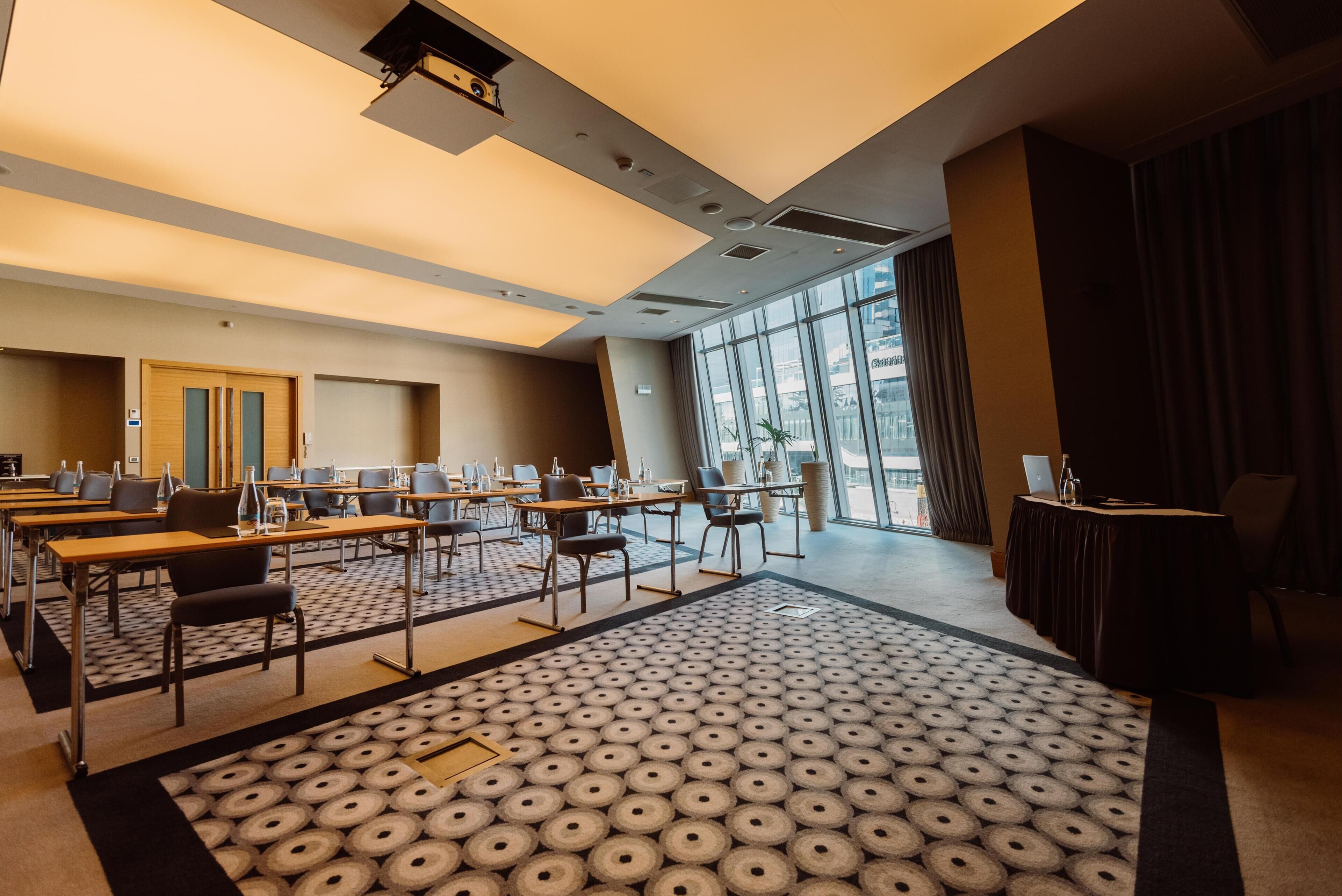 Une salle de conférence équipée de tables, de chaises et d’un tapis à motifs.