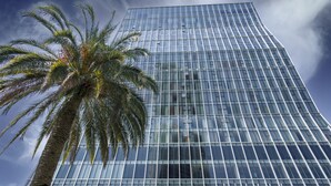 A modern glass skyscraper with a palm tree in the foreground. - Radisson Blu Hotel Batumi (Batumi)