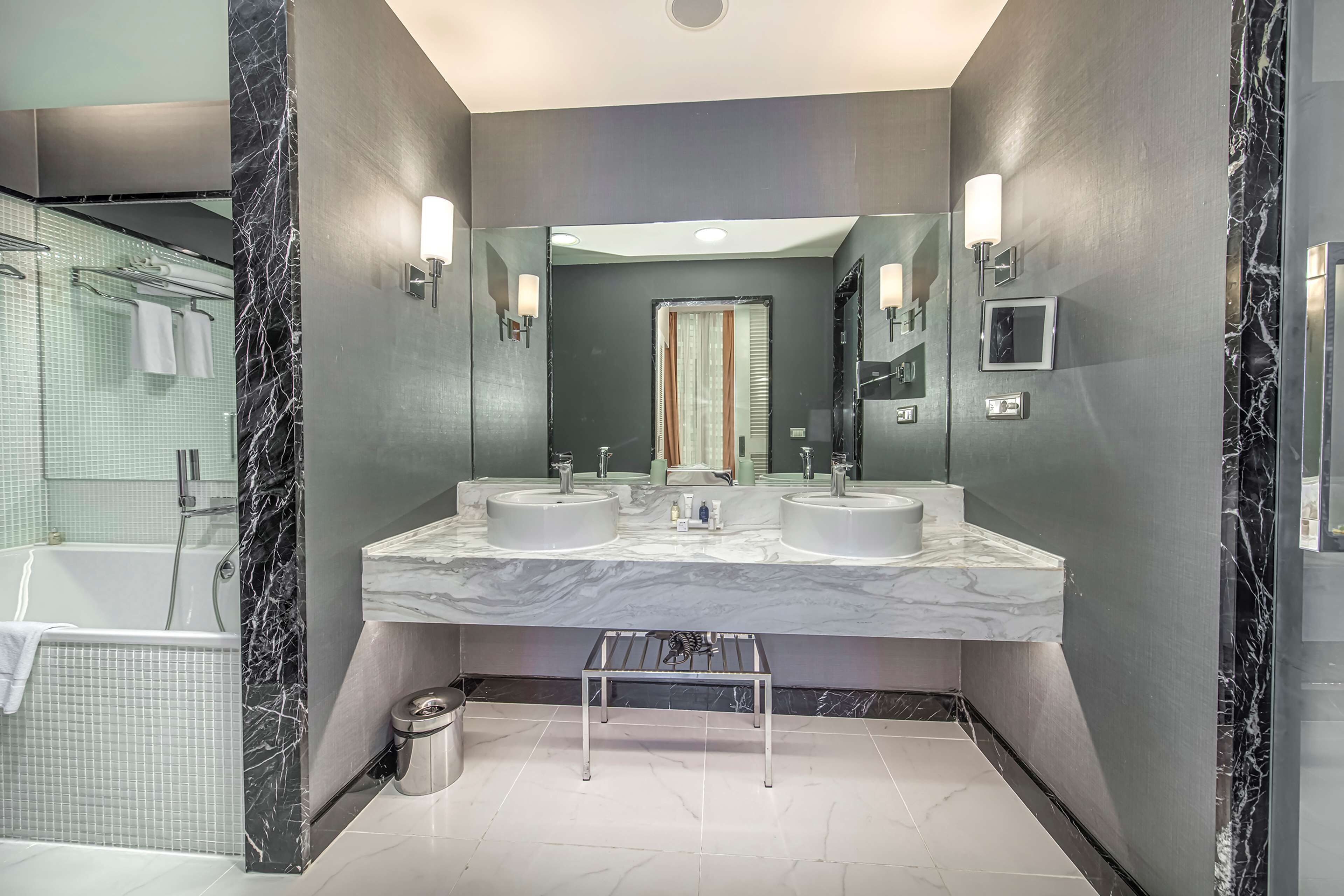 A modern bathroom with two sinks, a large mirror, and a shower area.