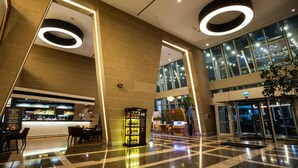 Eine moderne Lobby mit Bar, Sitzgelegenheiten, Automaten und Glastüren zum Eingang.