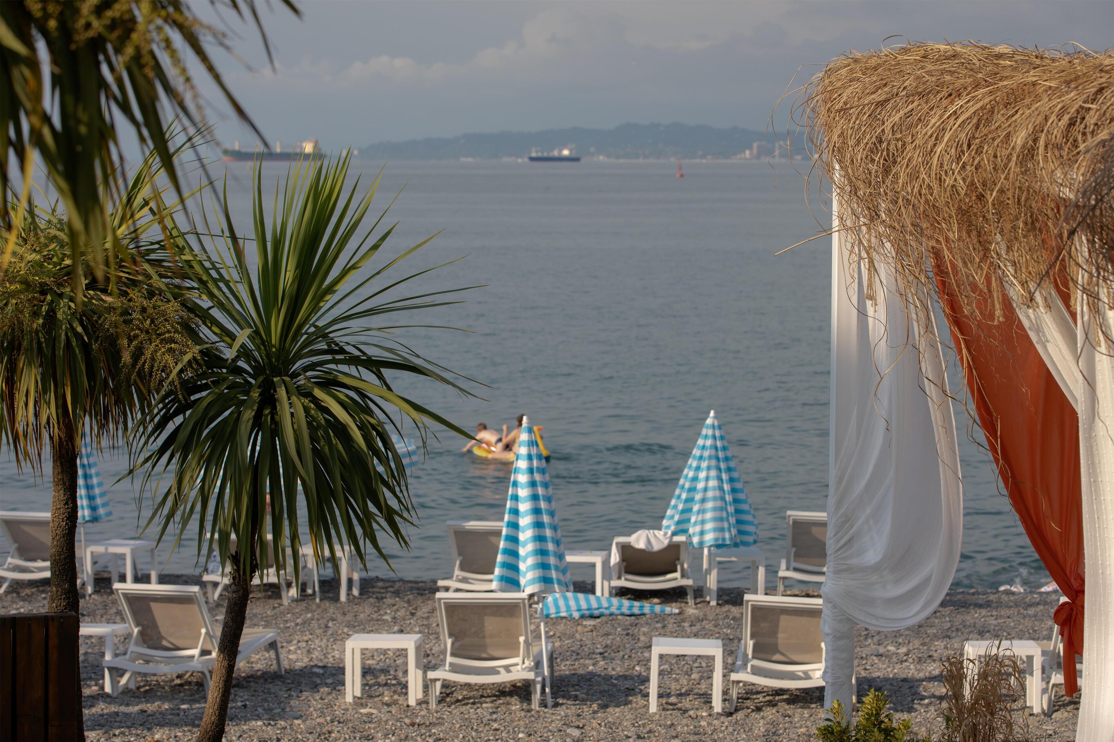 A beach with lounge chairs, umbrellas, and a view of the sea.