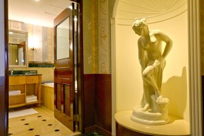 A bathroom with a marble sink, wooden vanity, and a statue of a woman.