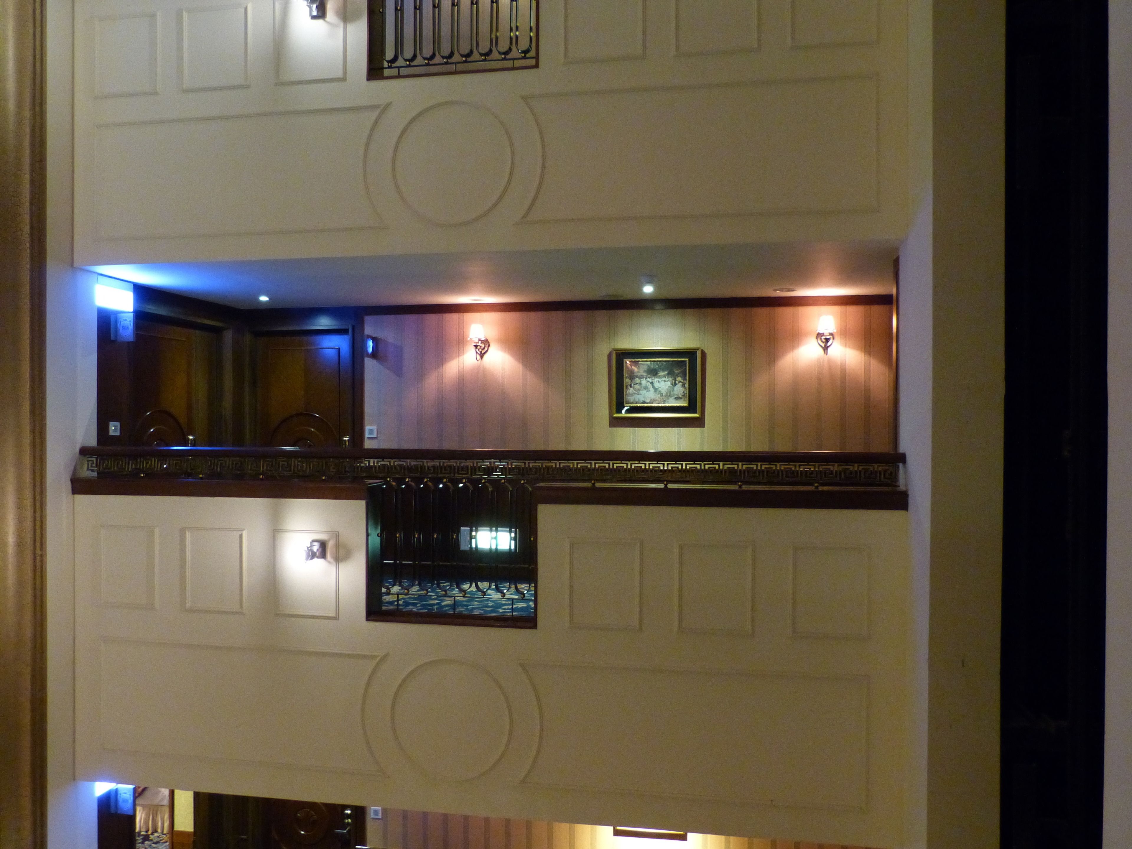 Un vestíbulo de hotel con techo alto, molduras decorativas, un cuadro en la pared y un ventanal con vistas.