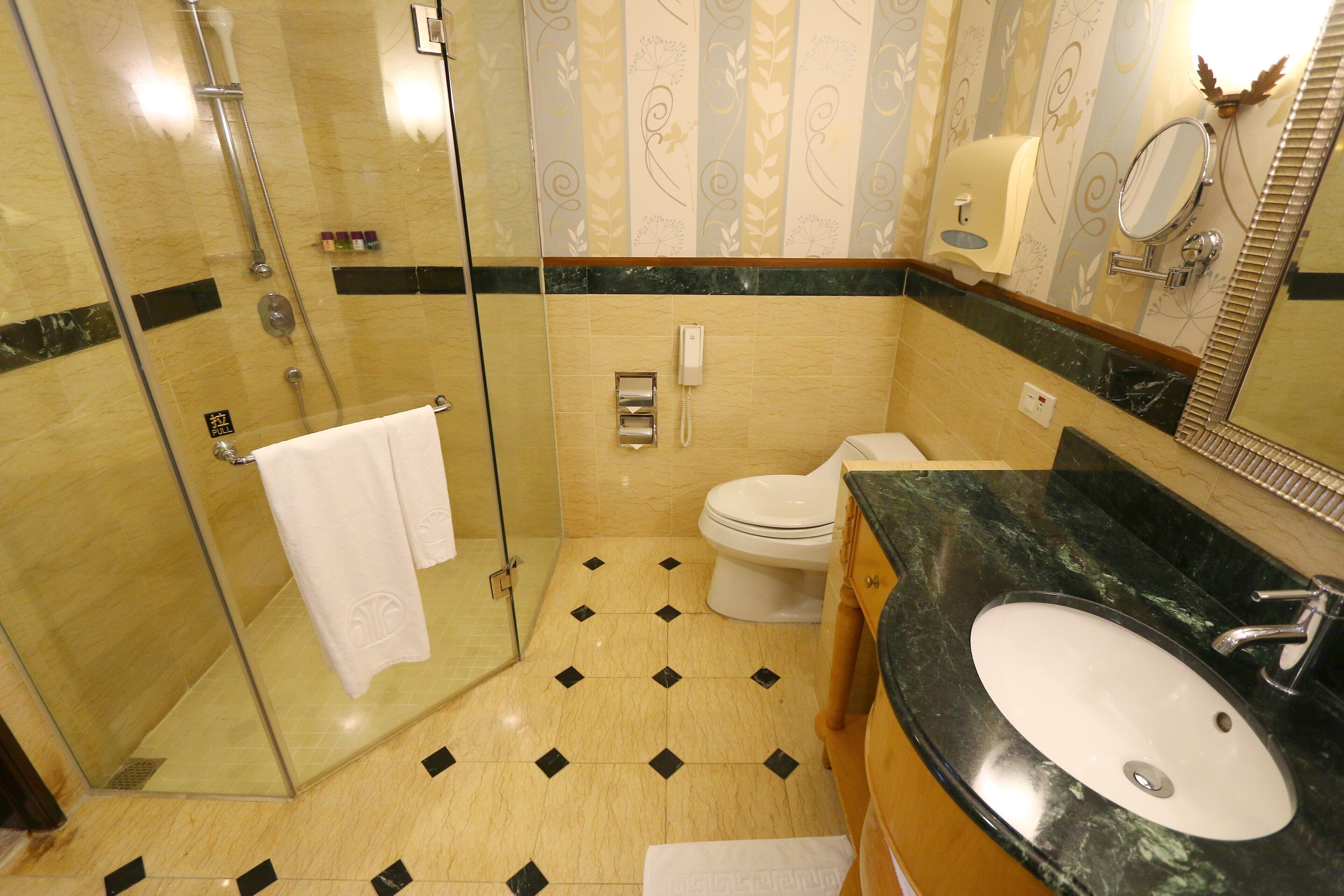 A bathroom with a glass-enclosed shower, a toilet, a sink, and a mirror.
