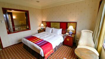 A hotel room with a bed, bedside tables, a chair, and a small table.