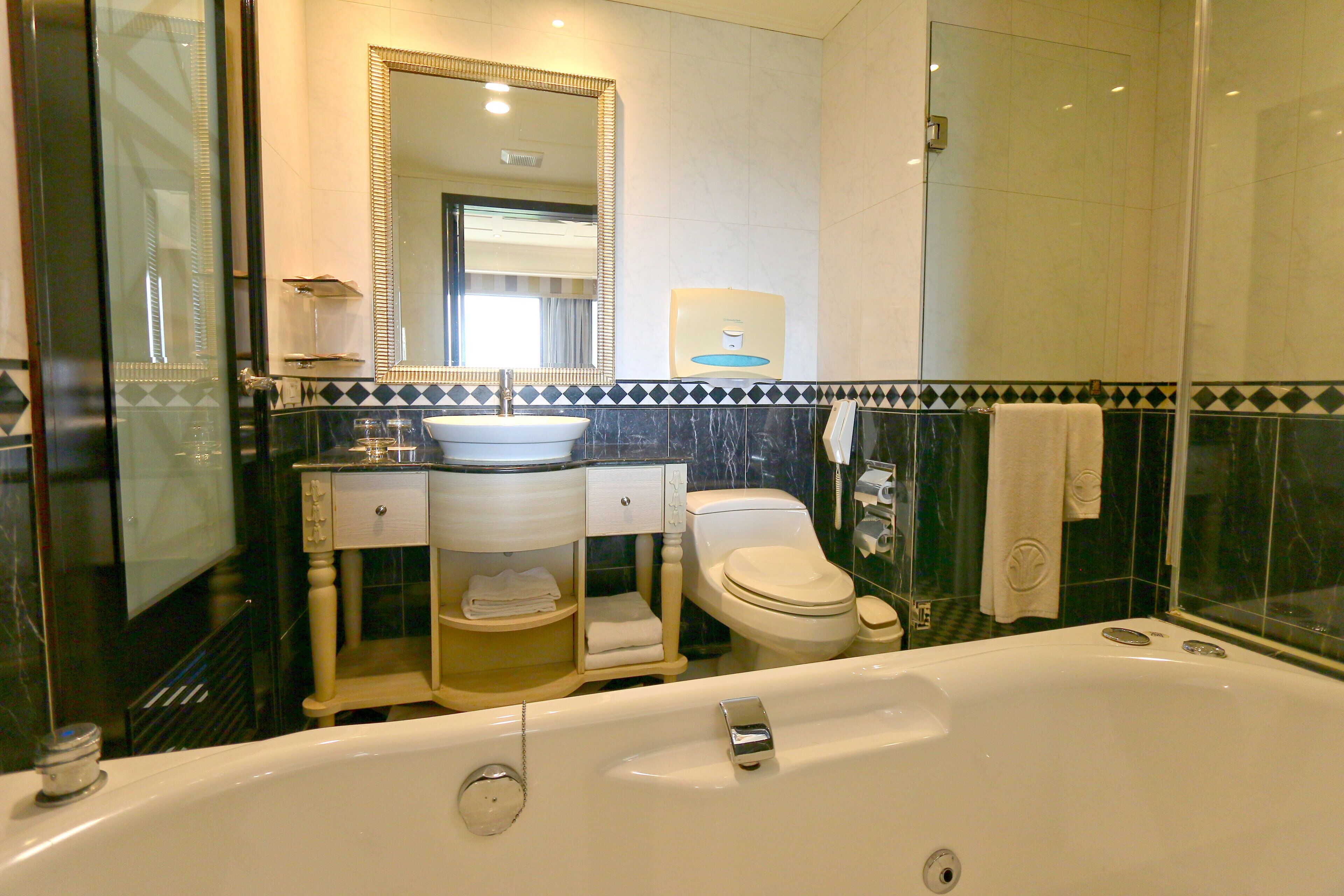 A bathroom with a bathtub, toilet, sink, and a large mirror.