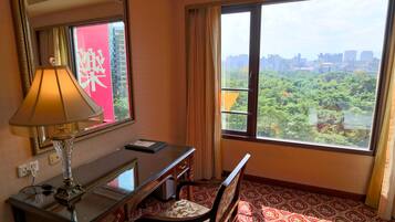 Une chambre d’hôtel équipée d’un bureau, d’une chaise et d’une grande fenêtre donnant sur le paysage urbain.