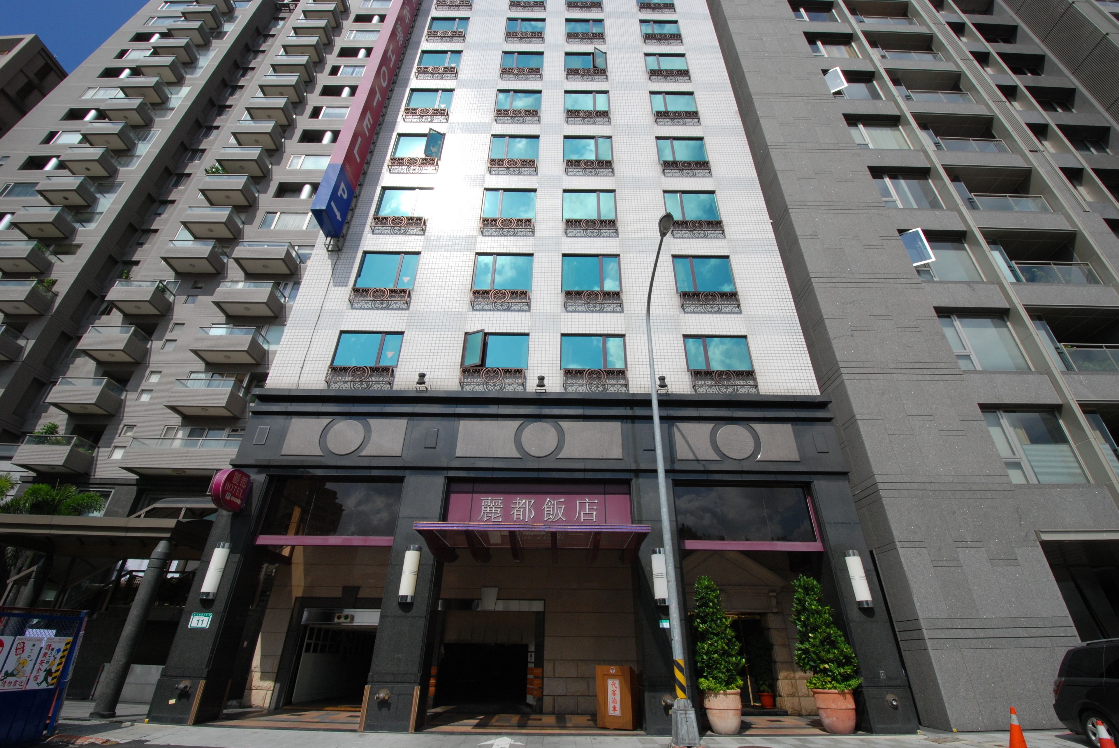 Un hotel moderno de gran altura con varios balcones, una entrada destacada y un letrero que indica que es un hotel.