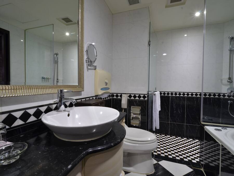 A modern bathroom with a black and white checkered floor, a white sink, a toilet, and a bathtub.