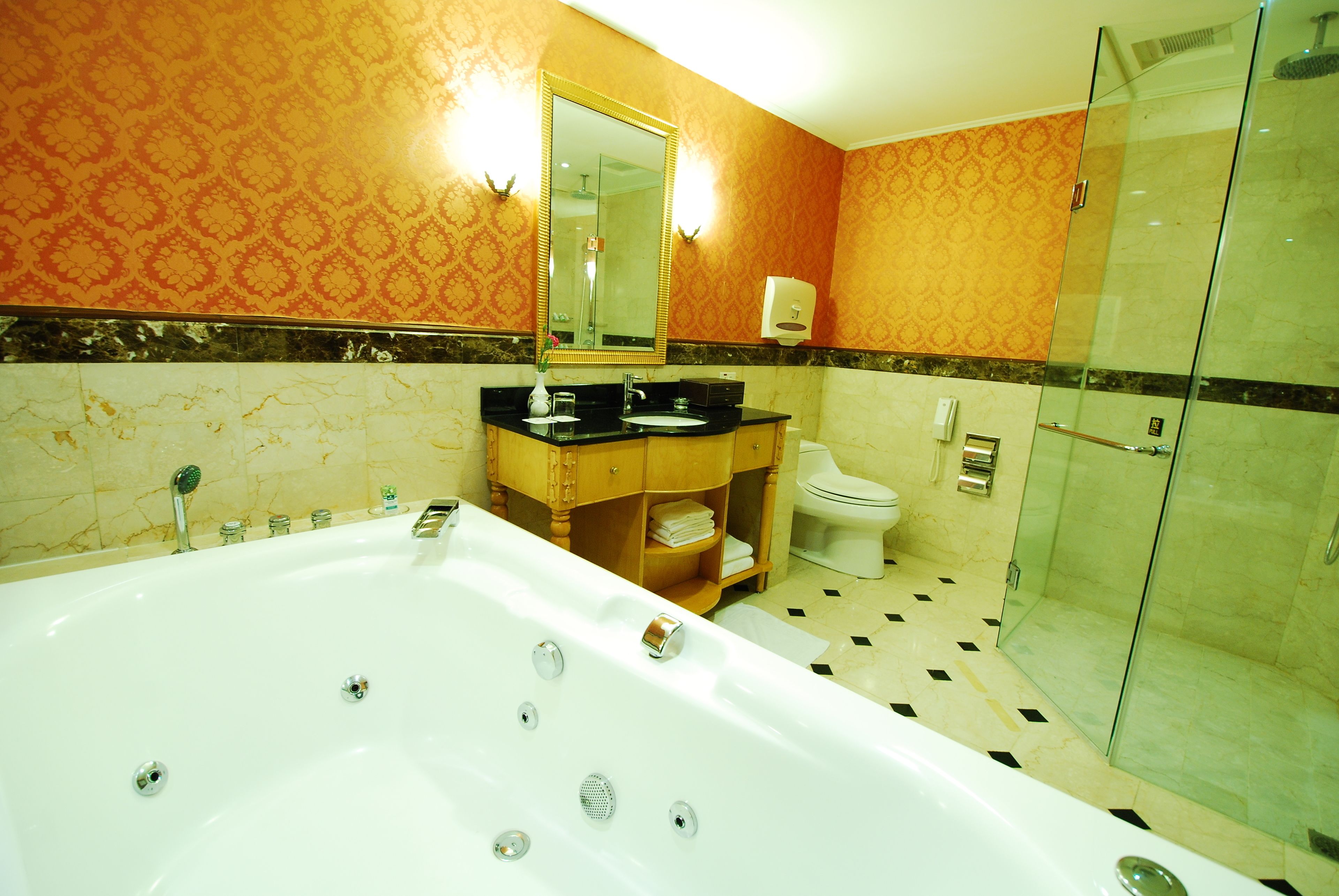 Un baño con una bañera grande, cabina de ducha con mampara de vidrio, inodoro y tocador con espejo.