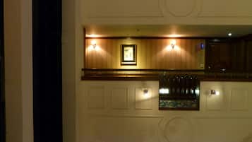 Um hall de hotel com área de bar, obras de arte emolduradas e luminárias fixadas na parede.