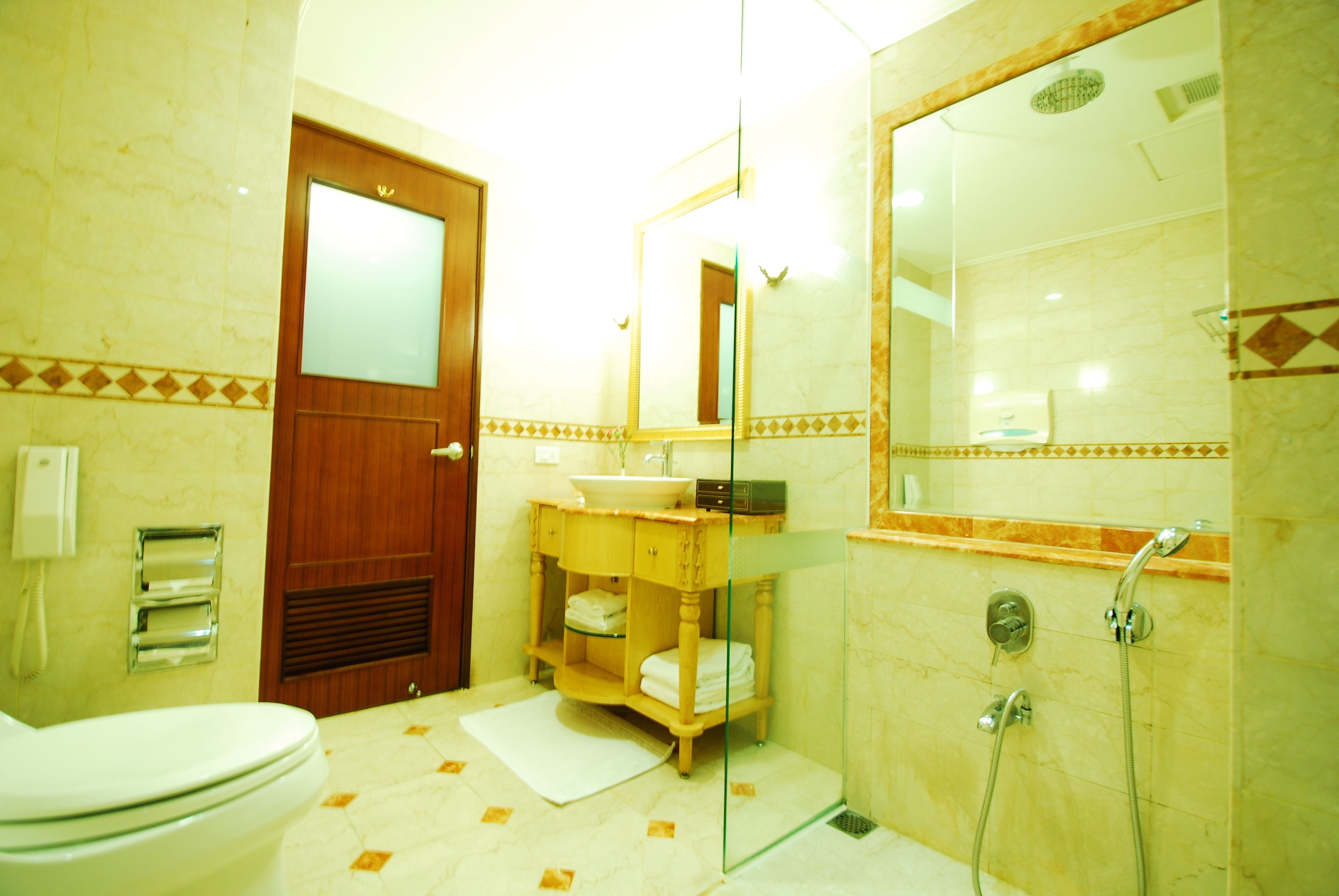 A bathroom with a toilet, sink, mirror, shower, and a towel rack.