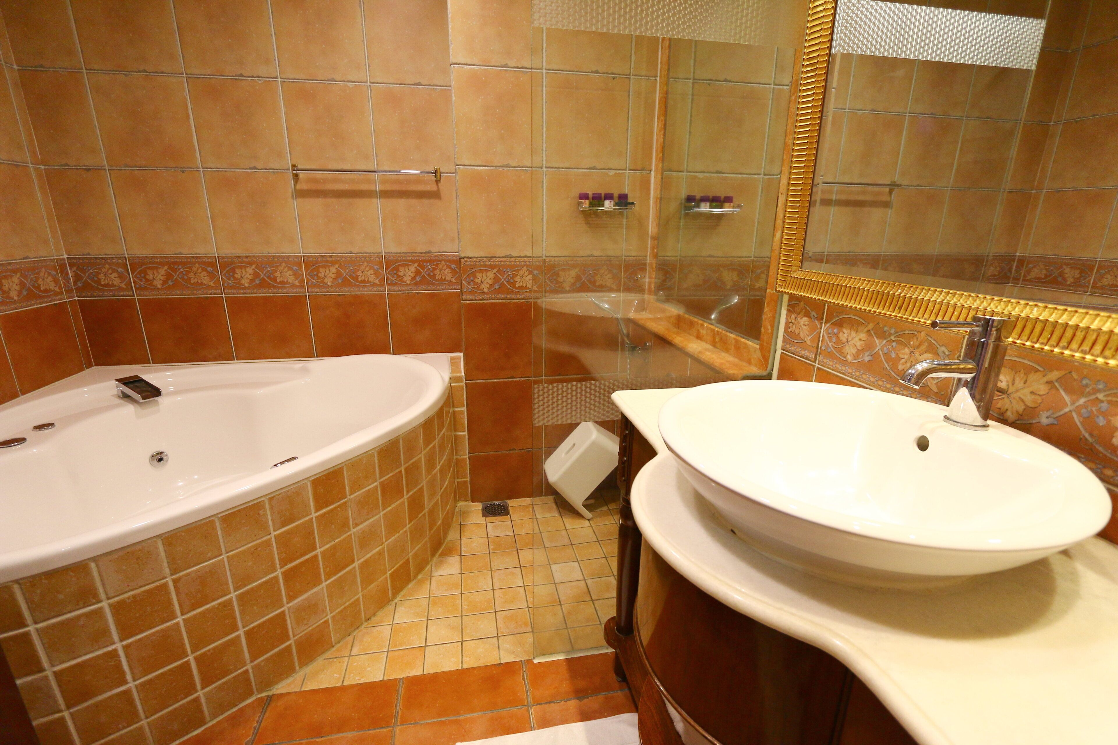 A bathroom with a bathtub, a sink, and a mirror.