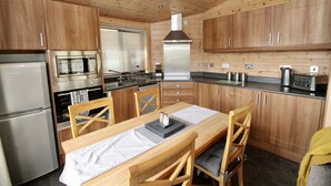 A compact kitchen with wooden cabinets, a stainless steel refrigerator, a microwave, a stove, and a sink.