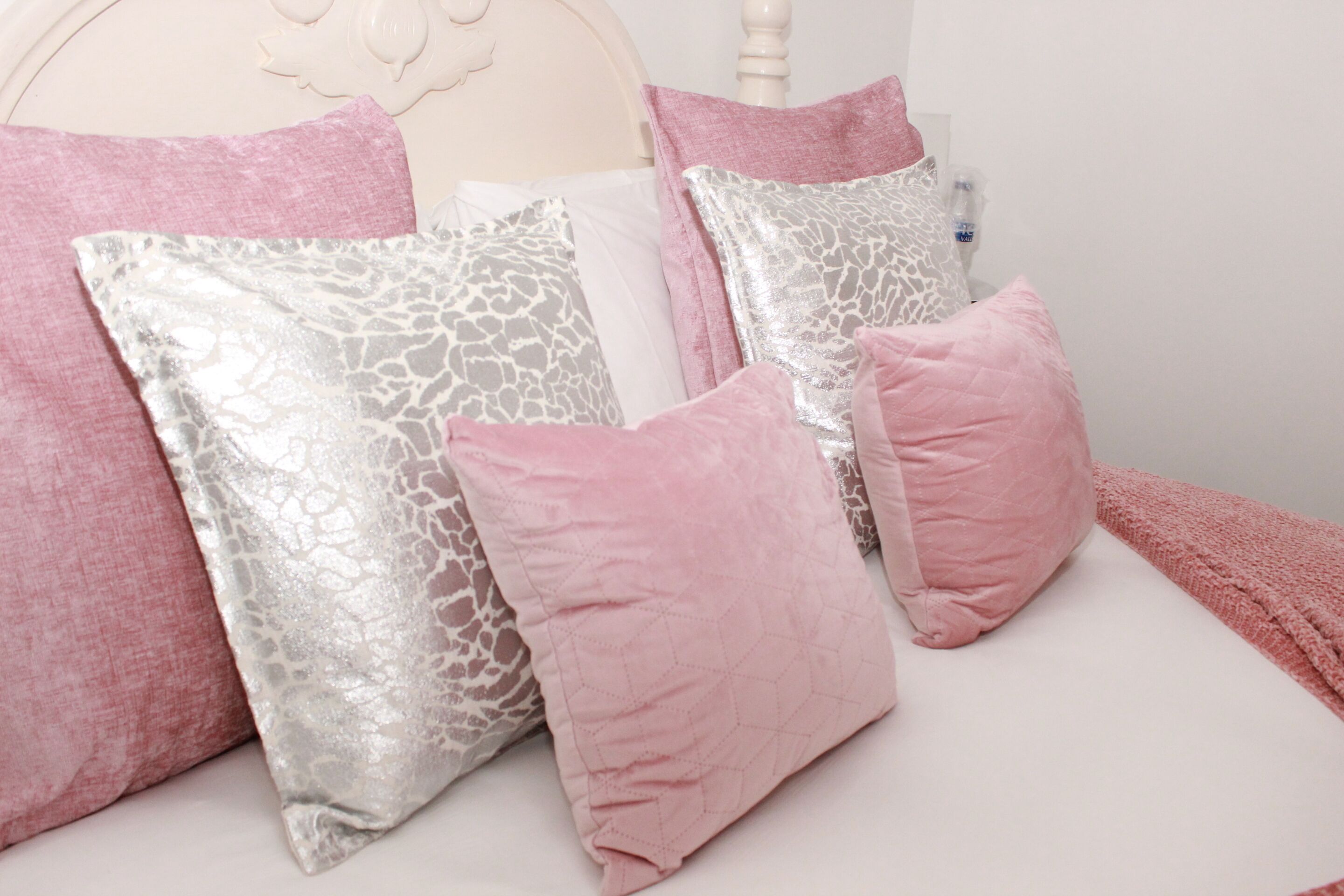 A bed with multiple pillows in various patterns and colors.