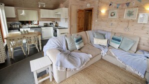 A cozy cabin interior with a dining area, kitchenette, and a sofa with decorative pillows.