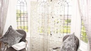 A room with two chairs, each with a grey patterned pillow and a white towel. A decorative white door with intricate designs is in the background.