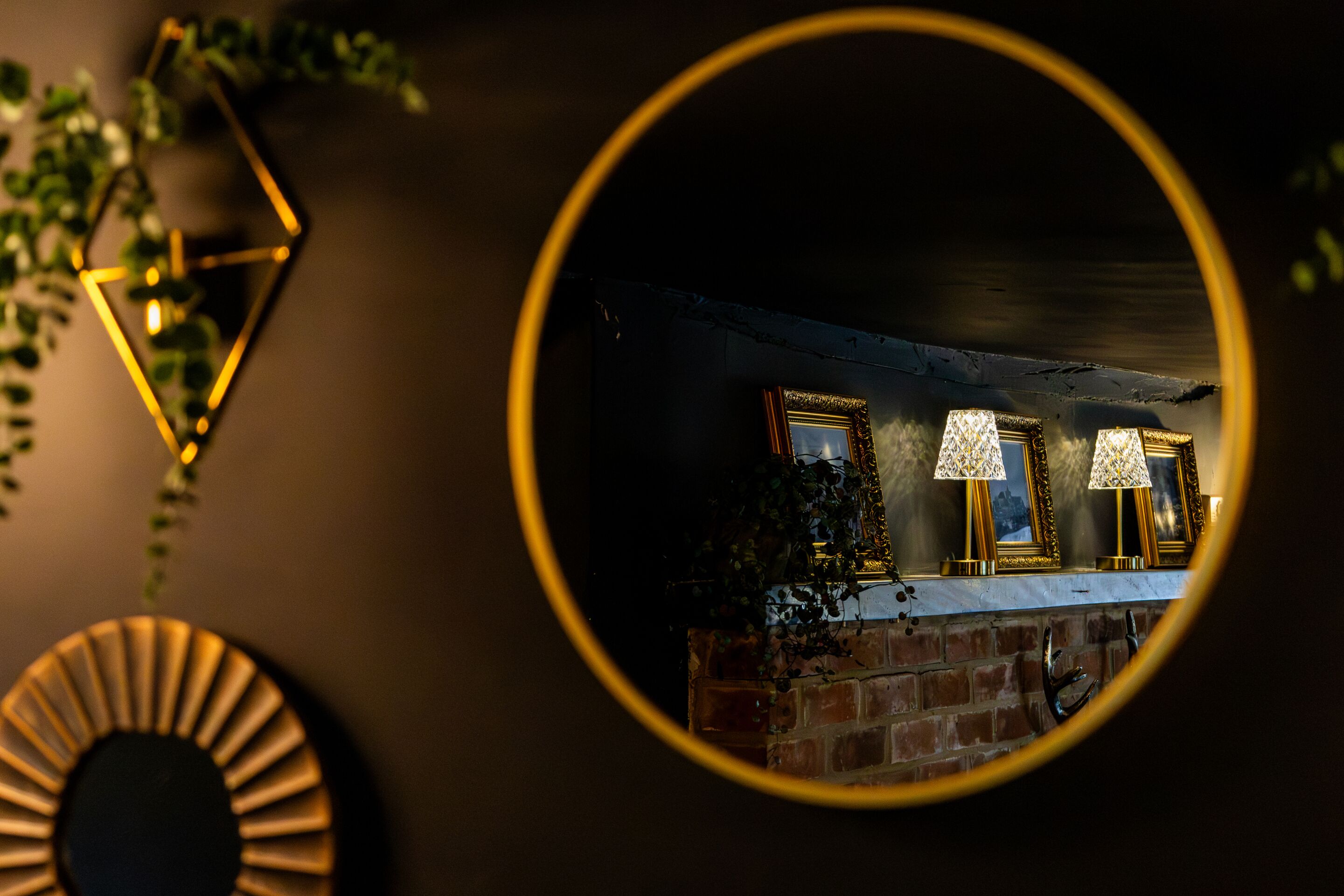 A round mirror reflecting two lamps and a brick wall.