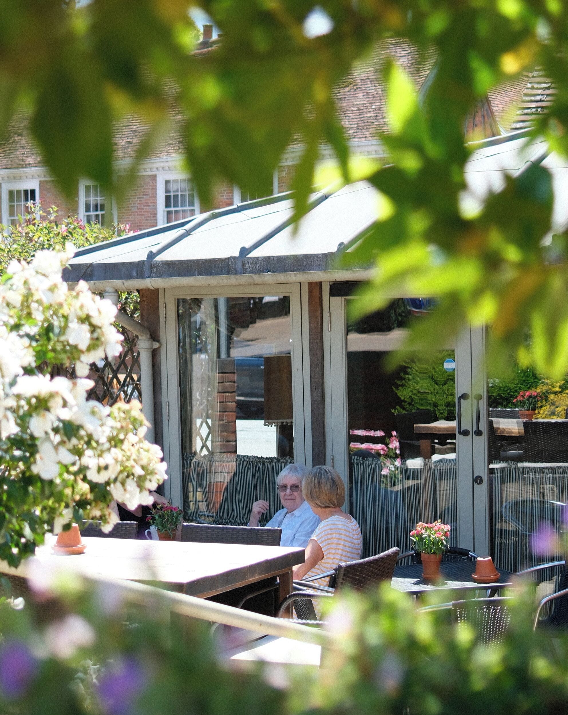 An outdoor seating area with a covered patio, tables, and chairs.